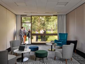 a waiting room with people standing outside a large window at Mercure Caen Centre Port De Plaisance in Caen