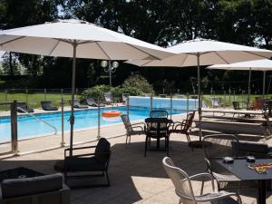 a patio with tables and chairs and umbrellas next to a pool at Novotel Bayeux in Bayeux