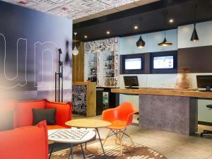 a restaurant with a bar with orange chairs and a table at ibis Paris Canal Saint Martin in Paris