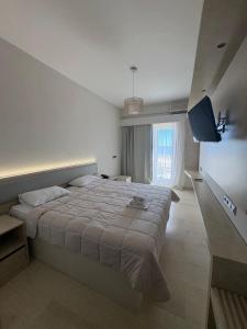 a bedroom with a large bed and a television at Zakros Beach hotel in Tolo +24 photos