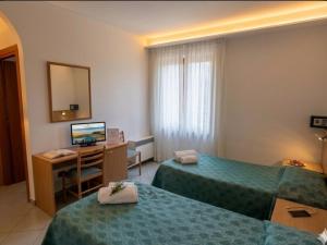 a hotel room with two beds and a desk with a computer at ALBERGO DELLA STAZIONE in Cairo Montenotte