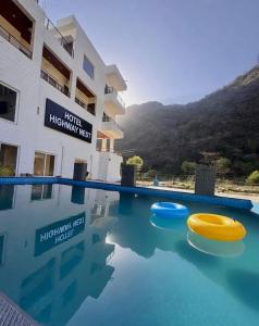 a swimming pool with two frisbees in front of a building at Hotel Highway Nest in Chamba