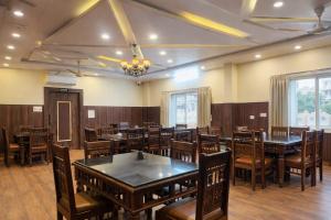 a dining room with wooden tables and chairs at Veda Resort in Udaipur