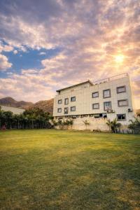a building with a grass field in front of it at Veda Resort in Udaipur