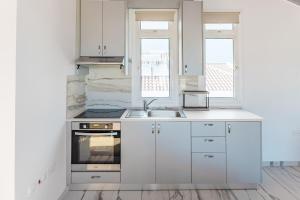 a kitchen with white cabinets and a sink and two windows at Modern Studio Loft in Central Larnaca with WiFi in Larnaca