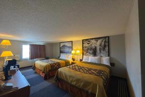 a hotel room with two beds and a desk at Super 8 by Wyndham Belle Fourche SD in Belle Fourche