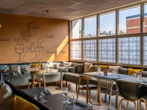 a restaurant with tables and chairs and windows at ibis Le Havre Centre in Le Havre