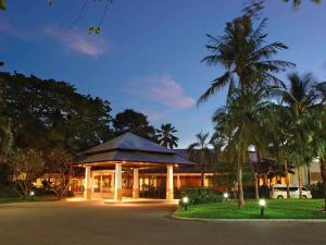 a building with palm trees in front of it at Novotel Rayong Rim Pae Resort in Klaeng