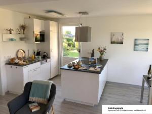 a kitchen with white cabinets and a counter top at Ferienhaus Strandläufer in Langballig +23 photos