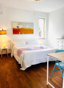 a white bedroom with a bed and a painting on the wall at La volpe e l'uva in Lavagno