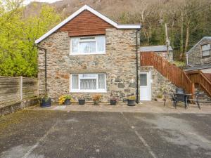 a stone house with potted plants in front of it at Ground Floor Apartment in Porthmadog