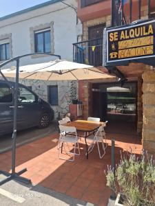 a table and chairs under an umbrella on a patio at El Fumvial in Arnuero