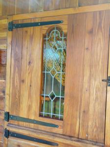 a door with a window in a wooden wall at Roulotte et Cabane Par Hasard in Saint-Bressou