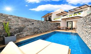 a house with a swimming pool in front of a brick wall at Aelia Suites in Agios Nikolaos