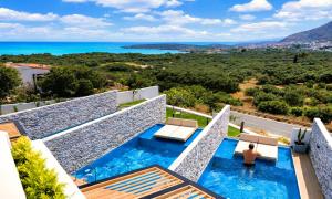 a villa with a swimming pool and the ocean at Aelia Suites in Agios Nikolaos