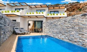 a villa with a swimming pool in front of a house at Aelia Suites in Agios Nikolaos