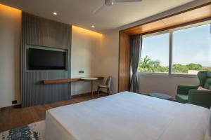 a hotel room with a bed and a tv at Radisson Resort & Spa Sasan Gir in Junagadh