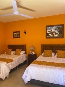 two beds in a room with orange walls at CASONA DOS VIDAS in El Sauz Tequisquiapan