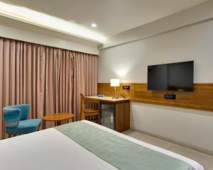a hotel room with a bed and a flat screen tv at The Qubice Hotel, Kolhapur in Kolhapur