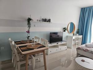 a living room with a dining room table and a television at Caesar Resort Lux Studio Apt in Trikomo