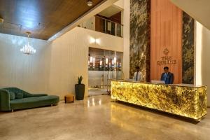 a lobby with a gold counter and a green couch at The Qubice Hotel, Kolhapur in Kolhapur +129 photos