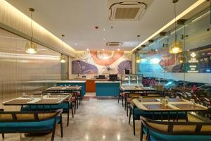 a restaurant with tables and chairs and a counter at The Qubice Hotel, Kolhapur in Kolhapur