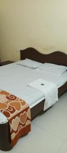 a bed with white sheets and a brown and white comforter at Kihim Beach Resort in Kīhīm