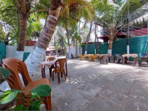 a patio with tables and chairs and palm trees at Kihim Beach Resort in Kīhīm