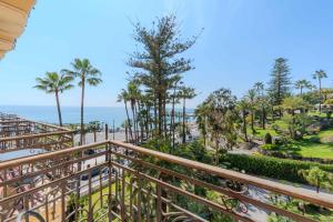 a balcony with a view of the beach and palm trees at Lolli Palace Hotel in Sanremo
