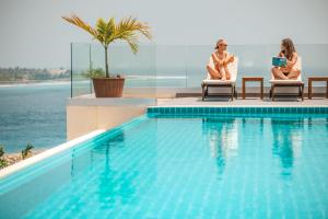 two women sitting in chairs next to a swimming pool at Season Paradise in Thulusdhoo