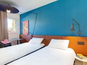 two beds in a room with a blue wall at ibis Marseille Timone in Marseille