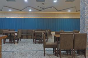 a dining room with tables and chairs and a blue wall at Serenity By The Ganges in Haridwār