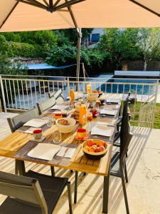 a wooden table with food on it with an umbrella at La Bellours Maison d Hôtes avec Piscine in Cahors