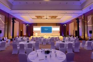 ein Festsaal mit weißen Tischen und Stühlen und einer Leinwand in der Unterkunft Hilton Doha in Doha + 121 Fotos