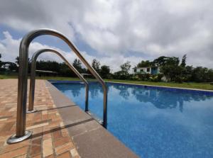 a swimming pool with metal hand rails next to a house at Lake Side Mantra in Khamshet