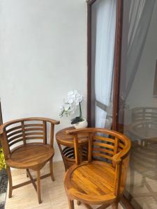 two wooden chairs and a table with a vase of flowers at Buana Hill in Kubupenlokan