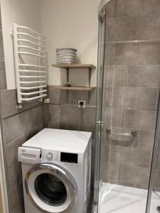 a washing machine in a bathroom with a shower at Apartament Aria in Ełk +6 photos