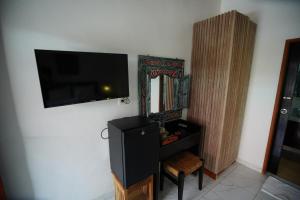 a living room with a tv and a dresser with a chair at The Galuh Pekutatan in Pulukan