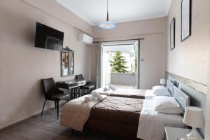 a bedroom with two beds and a desk and a window at Hotel Koutriaris in Distomo