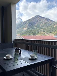 a table with two cups on a balcony with mountains at Apartment Lisa Hinterstoder in Hinterstoder