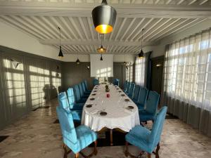 a dining room with a long table and blue chairs at Hotel La Chaumiere in Dole