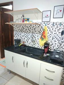 a kitchen with a sink and a black counter top at Kitnet Harmonia in Campo Grande