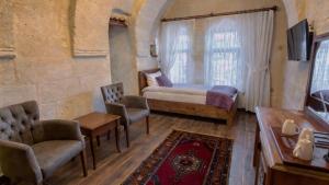 a bedroom with a bed and chairs and a tv at Göreme Rock Cave in Göreme