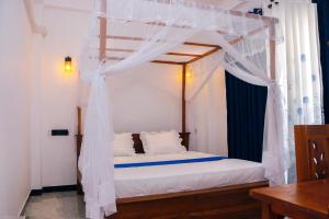 a bedroom with a canopy bed with white curtains at Malika homestay in Midigama East