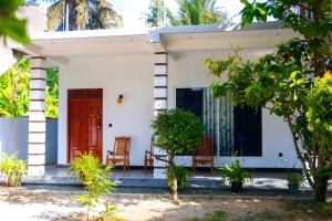 a house with two chairs and a red door at Malika homestay in Midigama East