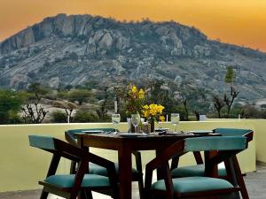 a table and chairs with a mountain in the background at Soma Jawai in Bijāpur