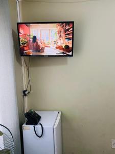 a flat screen tv hanging on a wall above a refrigerator at GLOBALNEST guest house in Cape Town
