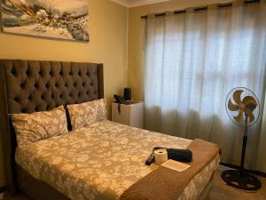 a bedroom with a bed and a fan next to a window at GLOBALNEST guest house in Cape Town