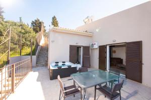 a patio with a glass table and chairs at Scorpina Horizon Villa in Kalamitsi