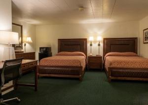 a hotel room with two beds and a desk at St. Mary’s Motel in Saint Marys